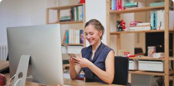 Woman using smartphone at desk in modern office