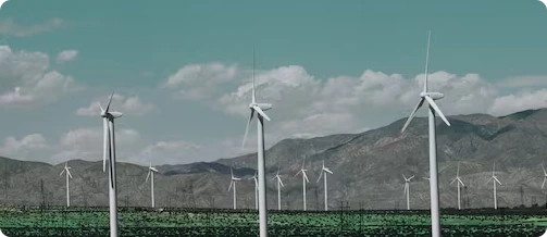 Wind turbines generating clean energy in a field with mountains.